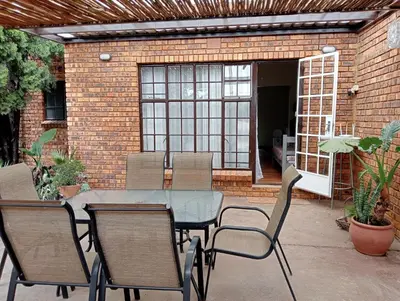 a patio with a table and chairs and a brick wall at Wapadrand Guest Suite in Pretoria