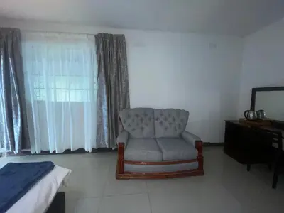 a bedroom with a chair and a bed and a mirror at Khaya Mnandi Leisure Suites in Pretoria