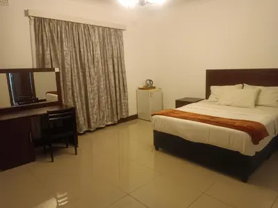 a bedroom with a bed and a desk and a television at Khaya Mnandi Leisure Suites in Pretoria