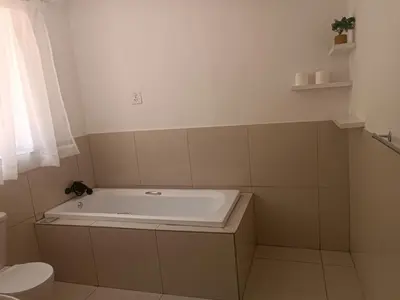 a bathroom with a bath tub and a toilet at Khaya Mnandi Leisure Suites in Pretoria