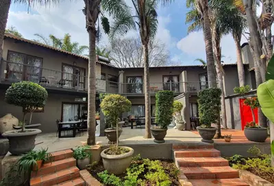 a courtyard with palm trees and a building at Waterhouse Guest Lodge - Indus Street in Pretoria
