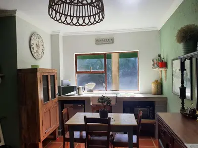 a kitchen with a table and a clock on the wall at Waterhouse Guest Lodge - Indus Street in Pretoria