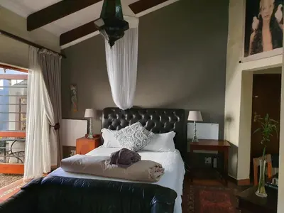 a bedroom with a bed with a black leather couch at Waterhouse Guest Lodge - Indus Street in Pretoria