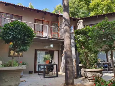 a building with a table and chairs and trees at Waterhouse Guest Lodge - Indus Street in Pretoria