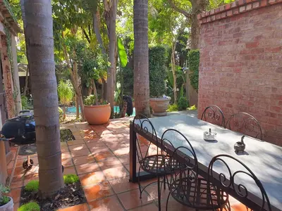 a patio with a table and chairs next to a brick wall at Waterhouse Guest Lodge - Indus Street in Pretoria