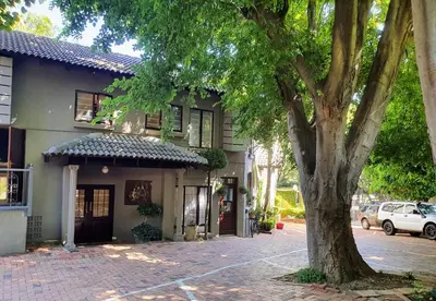 a building with a tree in front of it at Waterhouse Guest Lodge - Indus Street in Pretoria