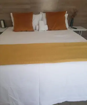 a bed with orange and white pillows on it at Riverside guesthouse in Phalaborwa