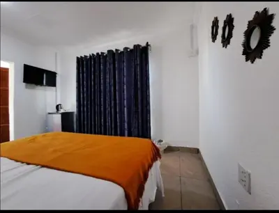 a bedroom with a bed with an orange blanket at Riverside guesthouse in Phalaborwa