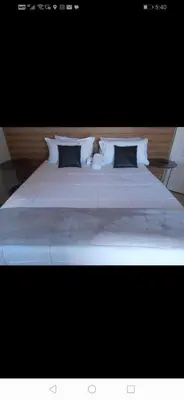a large bed with white sheets and pillows at Riverside guesthouse in Phalaborwa