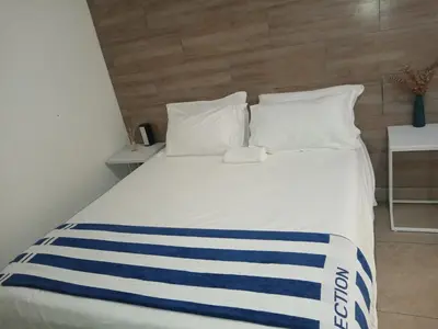 a white bed with blue and white stripes on it at Riverside guesthouse in Phalaborwa