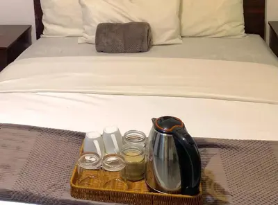 a tray with a tea kettle and glasses on a bed at Khaya Mnandi Leisure Suites in Pretoria