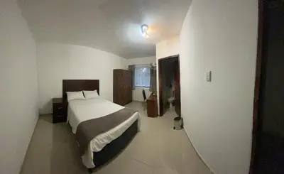 a bedroom with a bed in a white room at Khaya Mnandi Leisure Suites in Pretoria