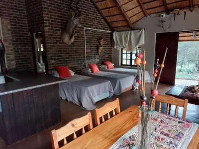 a bedroom with two beds in a room with a table at Tumuga Private Cottage Mokopane in Amatava