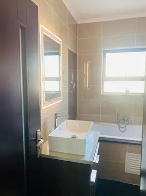 a bathroom with a white sink and a window at LuxuryHome in Midrand