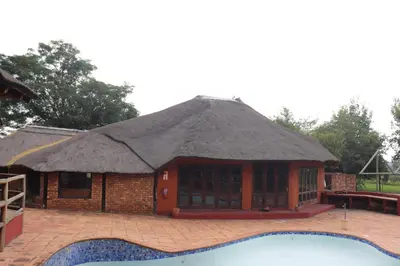 a hut with a thatched roof next to a swimming pool at Umnotho We Afrika House in Erasmus
