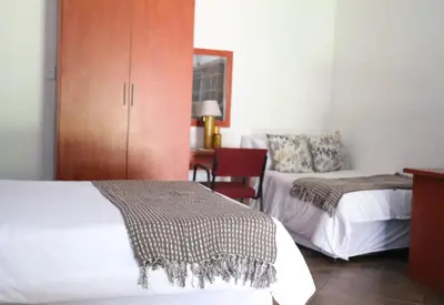a bedroom with two beds and a cabinet and a desk at Umnotho We Afrika House in Erasmus