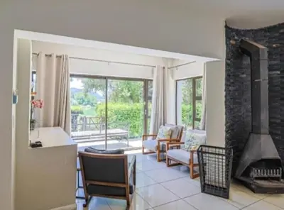 a living room with a fireplace and a living room with chairs at Modern 5BR Villa - Golf Course - Pecanwood Estate in Hartbeespoort
