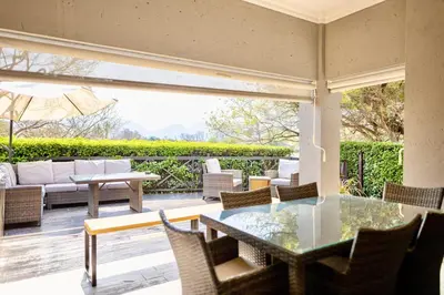an outdoor patio with a glass table and chairs at Modern 5BR Villa - Golf Course - Pecanwood Estate in Hartbeespoort
