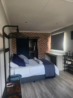a bedroom with a bed and a brick wall at @241 Enkeldoorn Guesthouse in Pretoria