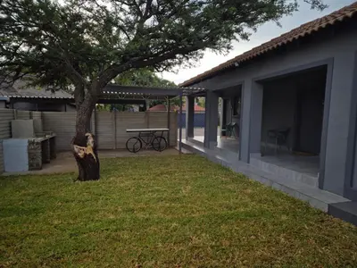 a yard with a table and a tree next to a house at @241 Enkeldoorn Guesthouse in Pretoria