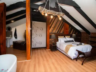a bedroom with a large bed in a attic at Crooked Cottage in Pelindaba