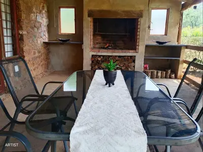 a glass table with a potted plant on a patio at Crooked Cottage in Pelindaba