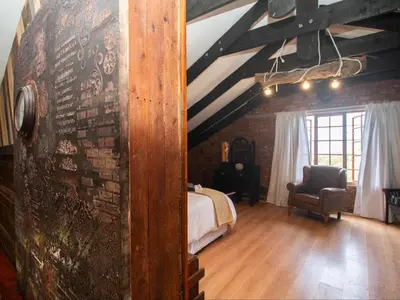 a bedroom with a bed and a brick wall at Crooked Cottage in Pelindaba