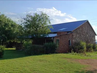 a brick house with a blue roof at Crooked Cottage in Pelindaba
