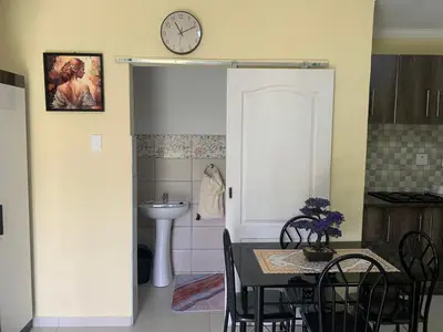 a dining room with a table and a clock on the wall at First derby Lodge in Benoni