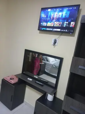 a desk with a mirror and a tv on a wall at First derby Lodge in Benoni