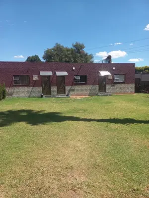 a red brick building with a large grass yard at First derby Lodge in Benoni