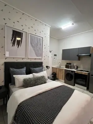 a bedroom with a large bed and a kitchen at Greencreek Riverwalk in Pretoria