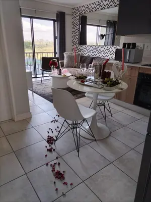 a kitchen and a living room with a table and chairs at Greencreek Riverwalk in Pretoria