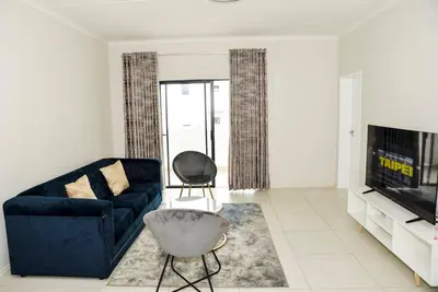 a living room with a blue couch and a tv at The Ellipse Palazzo Apartment in Midrand
