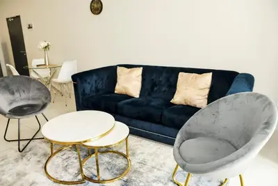 a living room with a blue couch and two chairs at The Ellipse Palazzo Apartment in Midrand