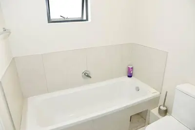 a white bathroom with a tub and a toilet at The Ellipse Palazzo Apartment in Midrand