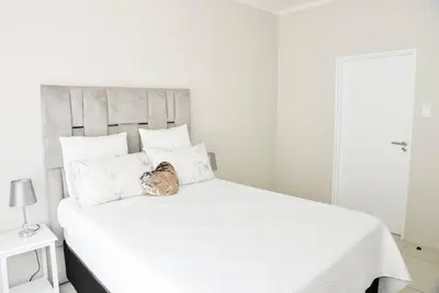 a white bed with a stuffed animal sitting on top of it at The Ellipse Palazzo Apartment in Midrand