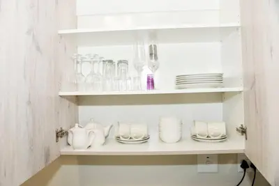 a white shelf with dishes and glasses on it at The Ellipse Palazzo Apartment in Midrand