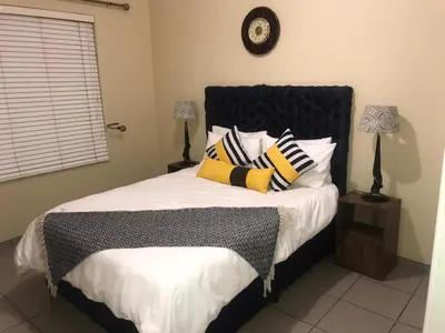 a bedroom with a bed with pillows and a clock on the wall at White Rose Cozy Apartment in Midrand