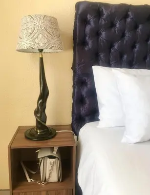 a lamp on a night stand next to a bed at White Rose Cozy Apartment in Midrand