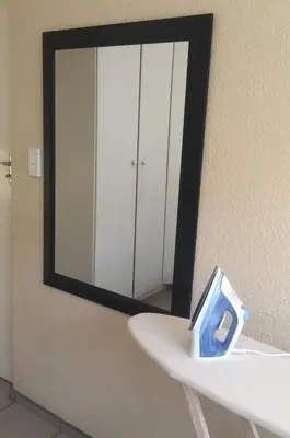 a mirror on a wall with a white sink at White Rose Cozy Apartment in Midrand