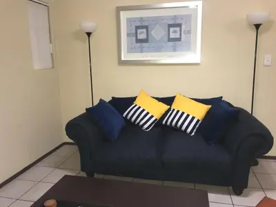 a black couch with pillows on it in a living room at White Rose Cozy Apartment in Midrand
