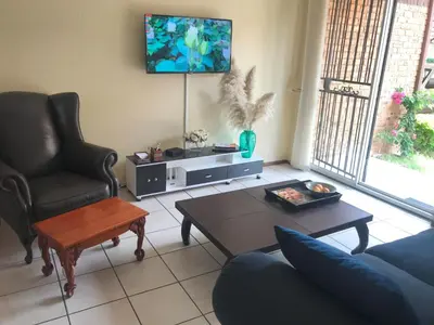 a living room with a couch and a table and a tv at White Rose Cozy Apartment in Midrand