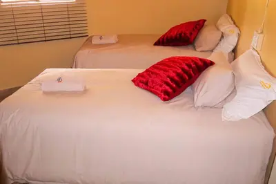 a bedroom with two beds with red pillows on them at Africa Self Catering Chalets - Manyeleti in Manyeleti Game Reserve