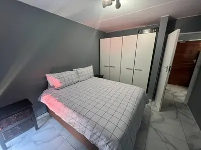 a small bedroom with a bed and a cabinet at Beyond Comfort Apartment in Pretoria