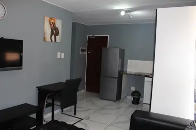 a living room with a table and a refrigerator at Beyond Comfort Apartment in Pretoria