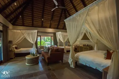 a bedroom with two beds and a chair at Inyati Game Lodge in Sabi Sand Game Reserve