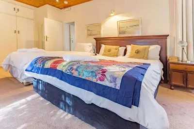 a bedroom with a large bed with a wooden headboard at Bay Tree Guest House in Pretoria