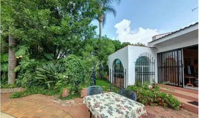 a patio with a table and chairs and a house at Bay Tree Guest House in Pretoria
