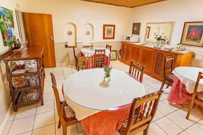 a dining room with two tables and a kitchen at Bay Tree Guest House in Pretoria